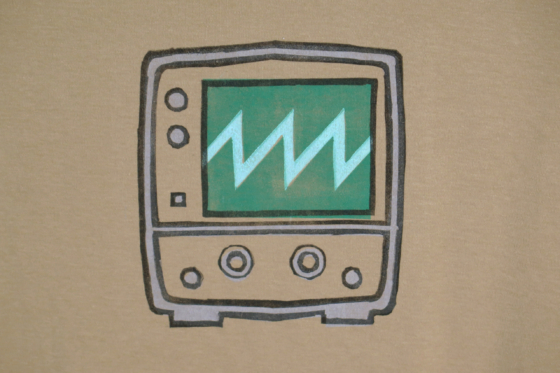 very close shot of the block print of an oscilloscope displaying a sawtooth waveform is hand printed centered over the chest area.
