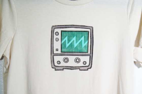 medium closeup of the block print of an oscilloscope displaying a sawtooth waveform hand printed centered over the chest area of the t-shirt.