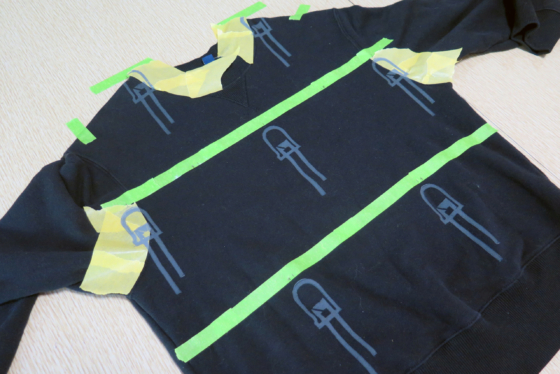 A photo of a black sweatshirt with lines of tape on the shirt. prints of LEDs are spaced on shirt using the tape as guides
