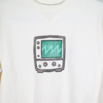 Medium close view of a block print of an oscilloscope displaying a sawtooth waveform is hand printed centered over the front chest area.