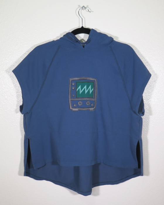 A navy sleeveless hooded shirt on a hanger hangs on a nail against a white wall. Showing the front. A block print of an oscilloscope with a sawtooth waveform displayed is hand printed in the center. The hoodie strings are pulled back to show the print more.