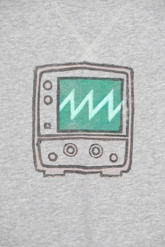 Close up of the block print of an oscilloscope displaying a sawtooth wave is hand printed on over the chest area.