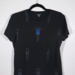 front of black t-shirt on hanger hanging on a nail against a white wall. It is hand printed with an LED design